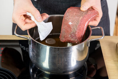 Fleisch und Gewürze in einem Teebeutel in die Brühe geben