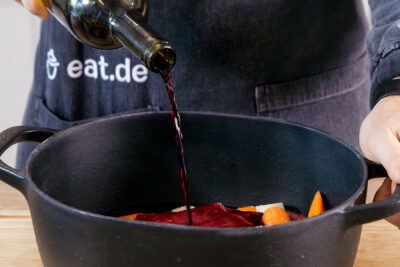 Wein zum Fleisch in den Bräter gießen