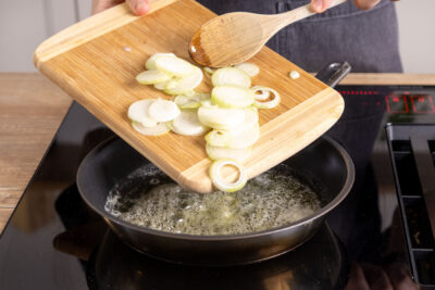 Zwiebelringe in die Pfanne geben