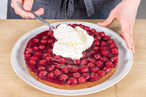 Sahnecreme auf der Kirschfüllung verteilen