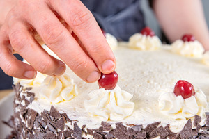 Kirschen auf die Sahnetuffs der klassischen Schwarzwälder Kirschtorte setzen