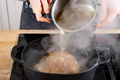 Schweinebraten mit Brühe begießen und im Ofen schmoren