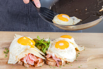 Spiegeleier auf Strammen Max mit Käse platzieren
