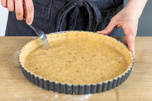 Mürbeteigboden der Schokotarte mit einer Gabel einstechen