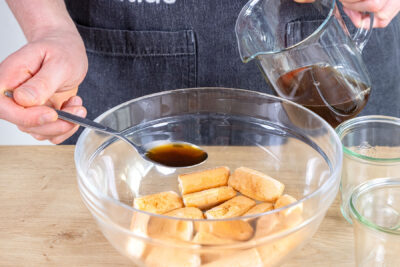 Löffelbiskuit mit Amaretto-Espresso-Mischung beträufeln
