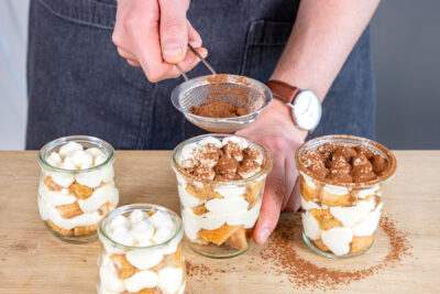 Tiramisu im Glas ohne Ei mit Kakaopulver bestäuben