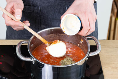 Gewürze und Creme fraiche zur Suppe geben