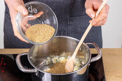 Knoblauch, Zwiebel und Grünkernschrot anbraten