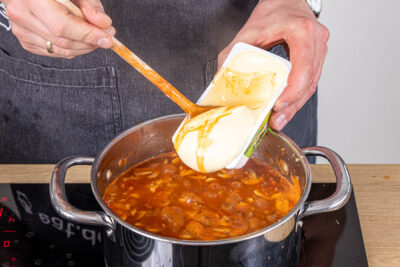 Schmelzkäse zur vegetarischen Pizzasuppe geben