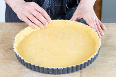 Mürbeteig in die Tarteform legen und andrücken