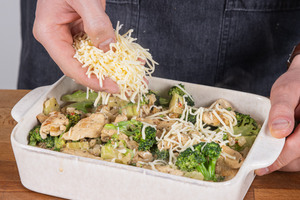 Cremigen Hähnchen-Brokkoli-Auflauf mit Käse bestreuen