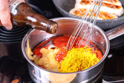 Ketchup, Apfelmus, Gewürze und Worcestersauce zur Cola geben
