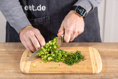 Frühlingszwiebeln in Ringe schneiden und Petersilie fein hacken