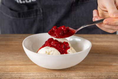 Heiße Himbeeren über Vanilleeis geben