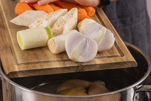 Suppengrün in den Topf zum Huhn geben
