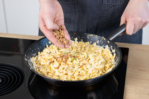 Käsespätzle mit Röstzwiebeln garnieren.
