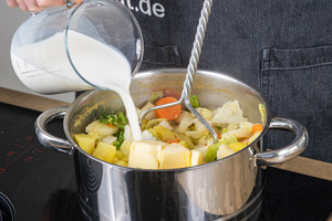 Butter und Milch zum Gemüse geben