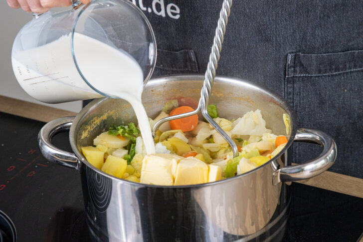 Butter und Milch zum Gemüse geben