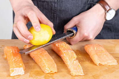 Zitronenschale über die Lachsfilets reiben