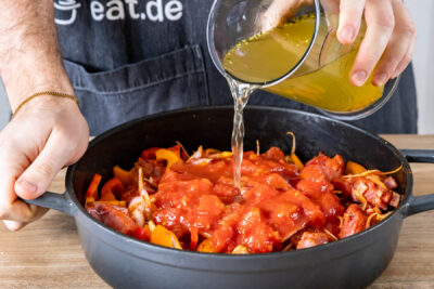 Brühe, Sahne und gehackte Tomaten in den Bräter geben