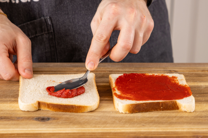 Tomatenmark auf Toast verteilen
