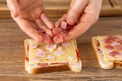 Salamiwürfel auf Toast geben