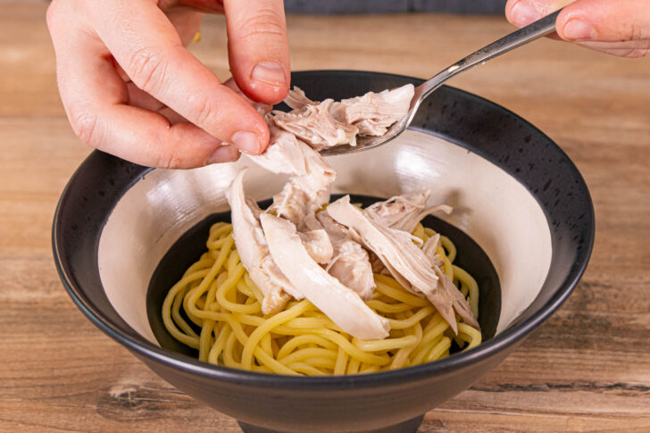Huhn, Sesam, Chili und Sprossen auf die Nudeln geben