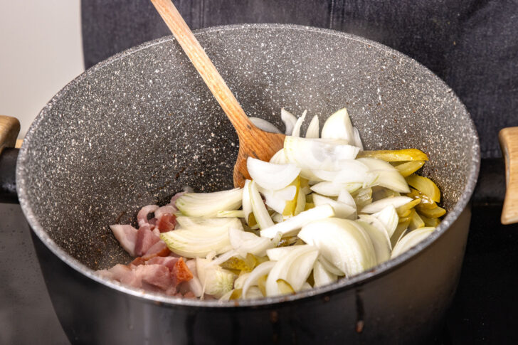 Zwiebeln und Gewürzgurken sowie Bauchspeck anbraten