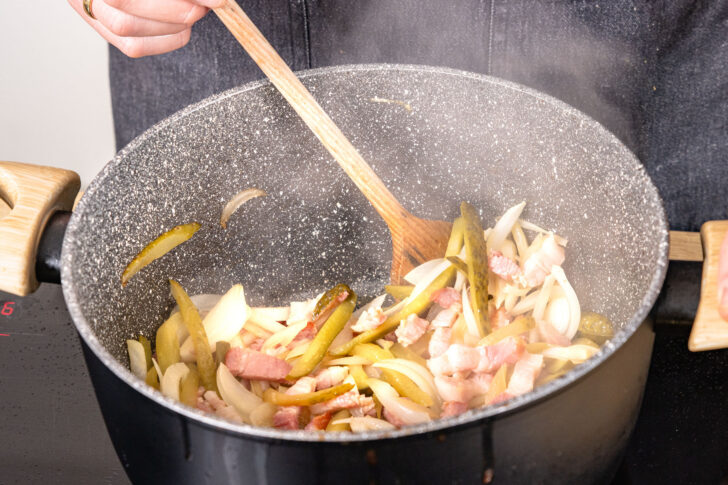 Zwiebeln und Gewürzgurken sowie Bauchspeck anbraten
