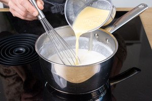 angerührtes Puddingpulver zur Milch in den Topf geben