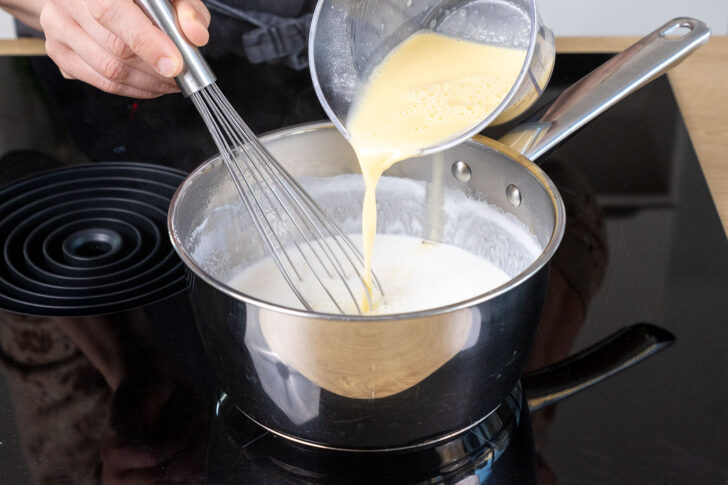 angerührtes Puddingpulver zur Milch in den Topf geben