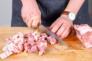Schweinenacken in mundgerechte Stücke schneiden