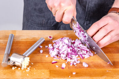 Knoblauch pressen und Zwiebel würfeln