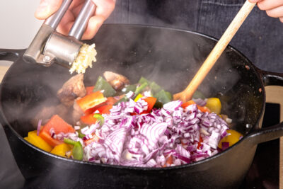 Paprika, Zwiebeln und Knoblauch in den Bräter geben