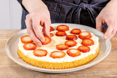 Erdbeerscheiben auf der Creme des Tortenbodens verteilen