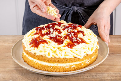 Spaghettieis-Torte mit weißer Raspelschokolade bestreuen