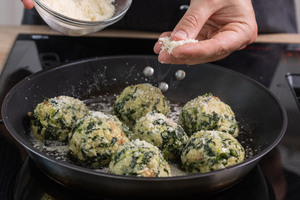 Spinatknödel in der Pfanne mit Parmesan bestreuen