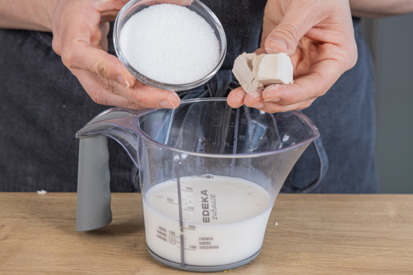 Zucker und Hefe mit lauwarmer Milch vermischen