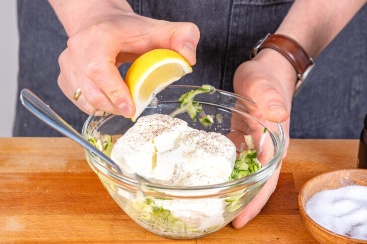 Quark, Gewürze und Zitronensaft zu Gurke geben