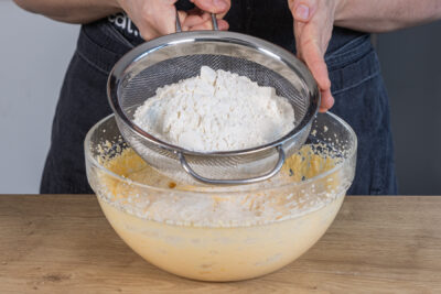 Mehl, Puddingpulver und Backpulver durch ein Sieb geben