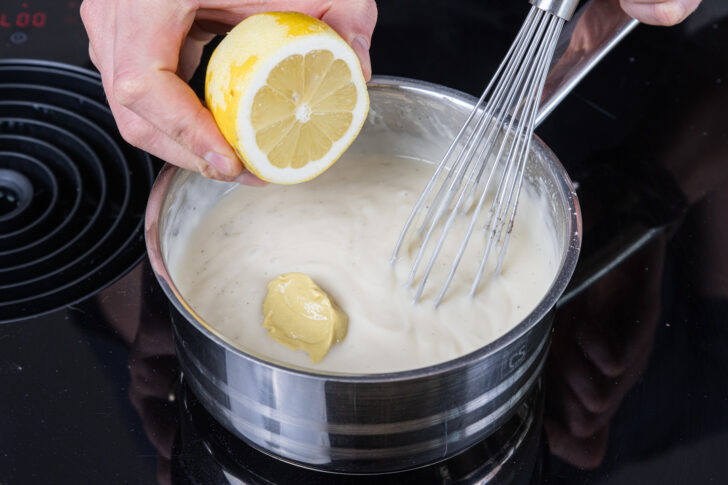 Senf und Zitronensaft zur Sauce Hollandaise geben