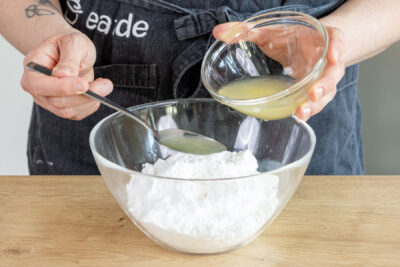 Zitronensaft zum Puderzucker geben