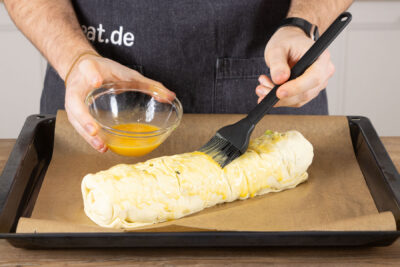 Den Strudel mit Eigelb bestreichen.