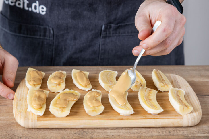 Erdnussmus über Bananen verteilen