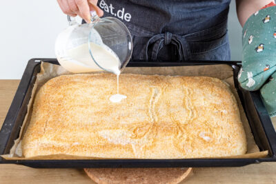 ahne auf den gebackenen Buttermilchkuchen mit Kokos gießen