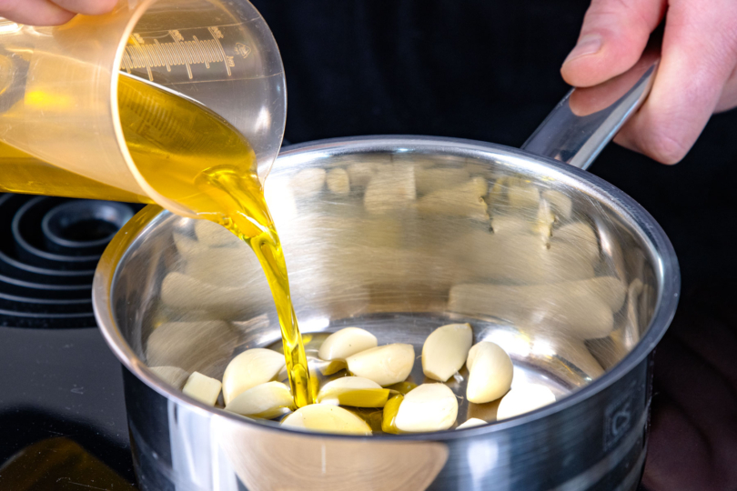 Raffiniertes Olivenöl zum Knoblauch gießen