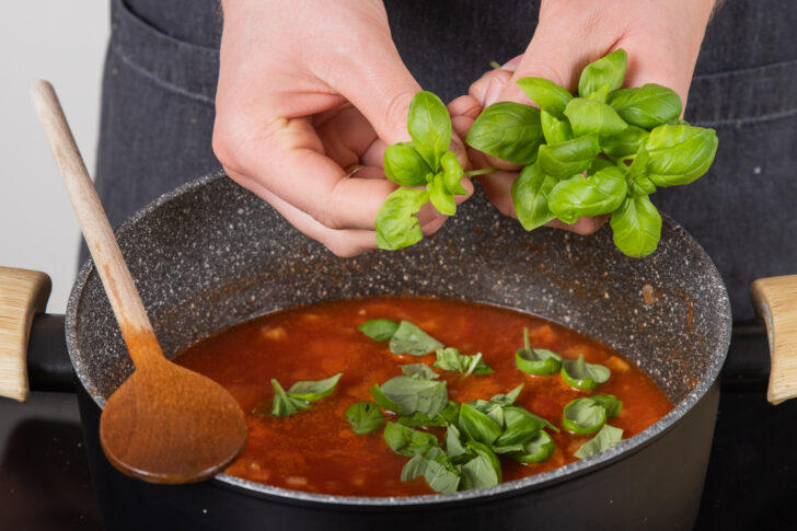 Basilikum zur Tomatensuppe geben