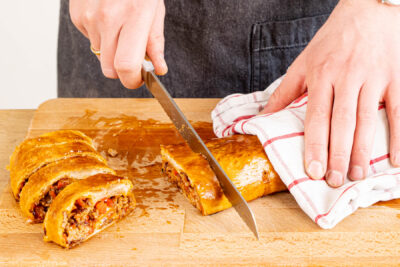 Hackfleisch-Käse-Blätterteigrollen in Scheiben schneiden