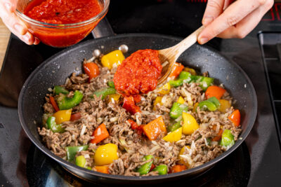 passierte Tomaten zur Hackfleischpfanne mit Paprika geben