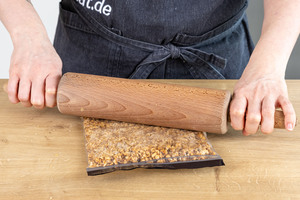Haselnusskrokant mit dem Nudelholz zerkleinern